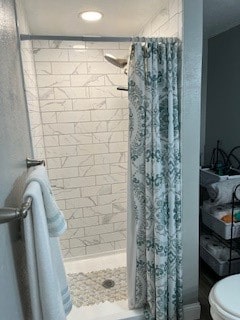 bathroom featuring walk in shower and toilet