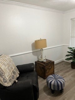 sitting room with hardwood / wood-style floors and crown molding