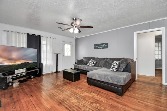 living room with a textured ceiling, ornamental molding, hardwood / wood-style floors, and ceiling fan