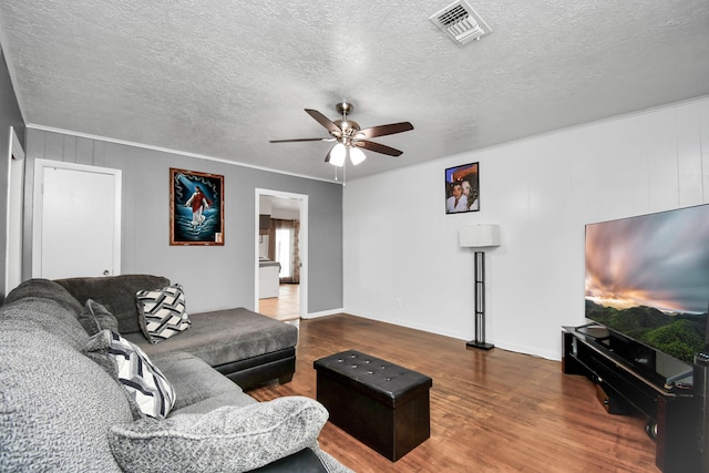 living room featuring ceiling fan, hardwood / wood-style flooring, crown molding, and a textured ceiling