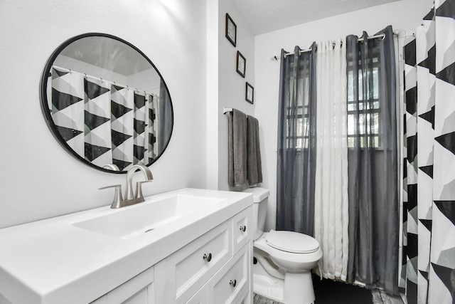 bathroom with vanity, toilet, and a textured ceiling