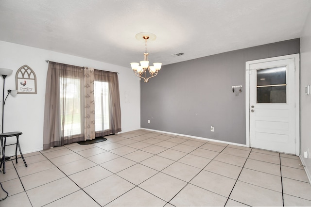 tiled spare room with an inviting chandelier