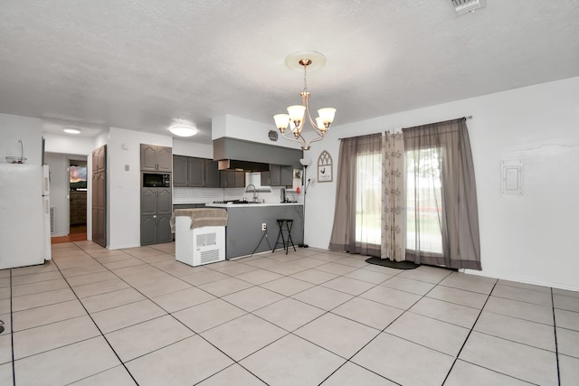 kitchen with light tile patterned flooring, black microwave, kitchen peninsula, white fridge, and backsplash