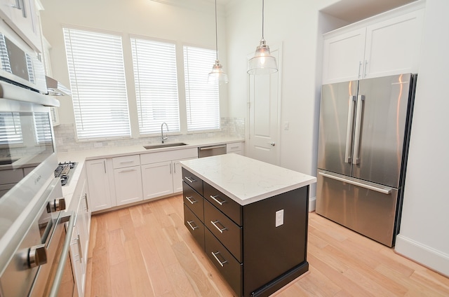 kitchen with pendant lighting, a kitchen island, light hardwood / wood-style flooring, stainless steel appliances, and white cabinets