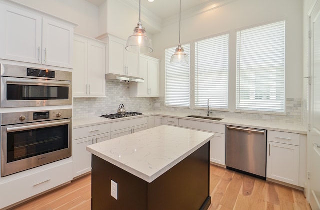 kitchen with white cabinets, sink, light hardwood / wood-style flooring, appliances with stainless steel finishes, and decorative light fixtures