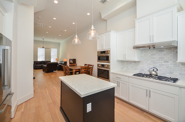 kitchen featuring hanging light fixtures, ornamental molding, tasteful backsplash, white cabinetry, and light wood-type flooring