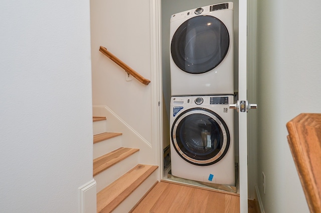 laundry area featuring hardwood / wood-style flooring and stacked washing maching and dryer