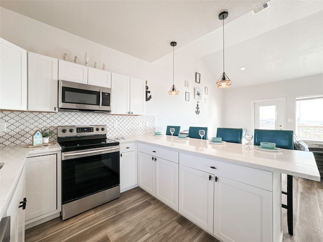 kitchen featuring a breakfast bar area, white cabinetry, kitchen peninsula, light hardwood / wood-style flooring, and appliances with stainless steel finishes