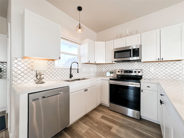 kitchen featuring wood-type flooring, sink, white cabinets, appliances with stainless steel finishes, and decorative light fixtures