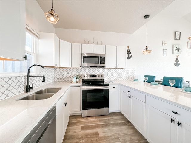 kitchen with decorative light fixtures, sink, stainless steel appliances, and white cabinets