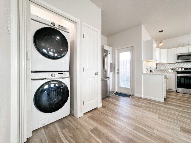 clothes washing area featuring light wood-type flooring and stacked washer / drying machine