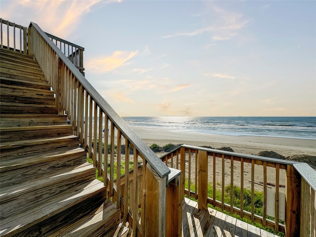 deck at dusk with a water view and a beach view