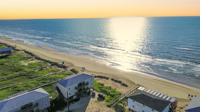 aerial view at dusk with a water view and a beach view