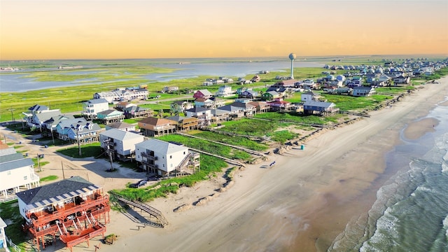 aerial view at dusk with a water view and a beach view