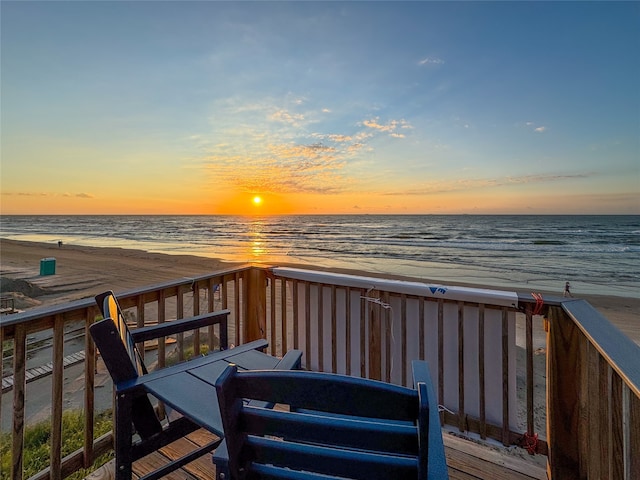 deck at dusk featuring a water view and a beach view