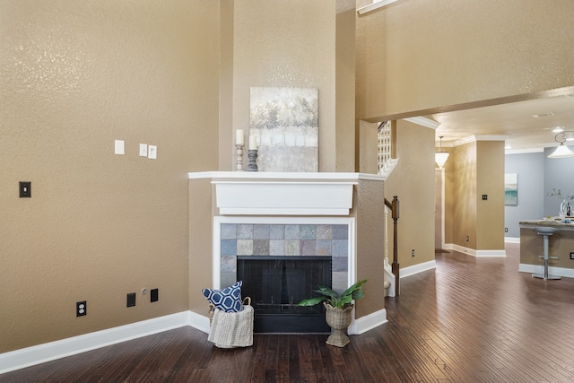 living room featuring hardwood / wood-style flooring, a tiled fireplace, and ornamental molding