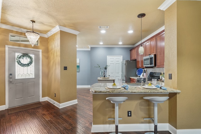 kitchen featuring dark hardwood / wood-style floors, kitchen peninsula, a kitchen bar, appliances with stainless steel finishes, and decorative light fixtures