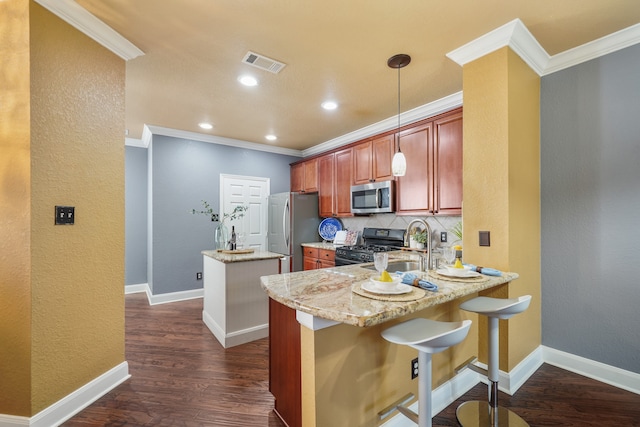 kitchen with appliances with stainless steel finishes, a kitchen breakfast bar, backsplash, kitchen peninsula, and decorative light fixtures