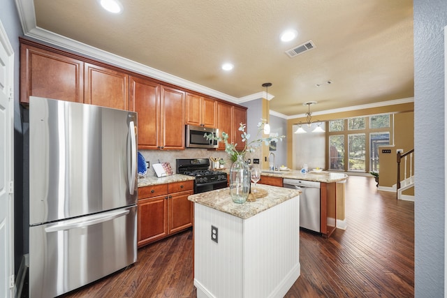 kitchen featuring hanging light fixtures, kitchen peninsula, a kitchen island, appliances with stainless steel finishes, and dark hardwood / wood-style floors