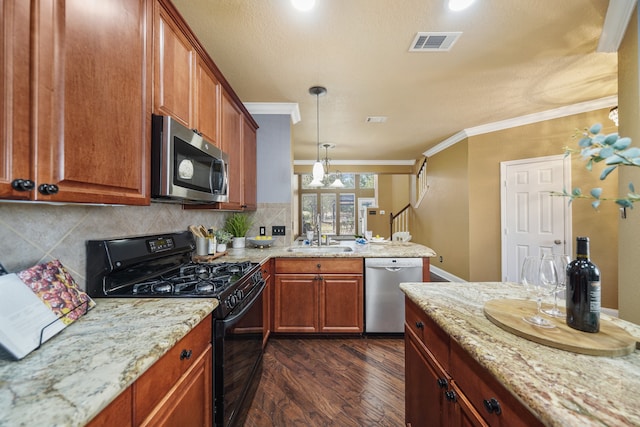 kitchen with appliances with stainless steel finishes, light stone countertops, pendant lighting, ornamental molding, and dark hardwood / wood-style floors