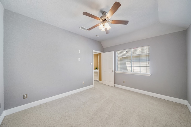 empty room with lofted ceiling, ceiling fan, and light colored carpet