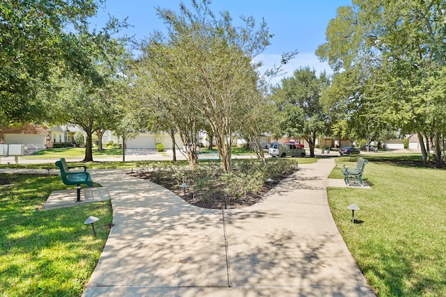 view of property's community featuring a yard and a garage