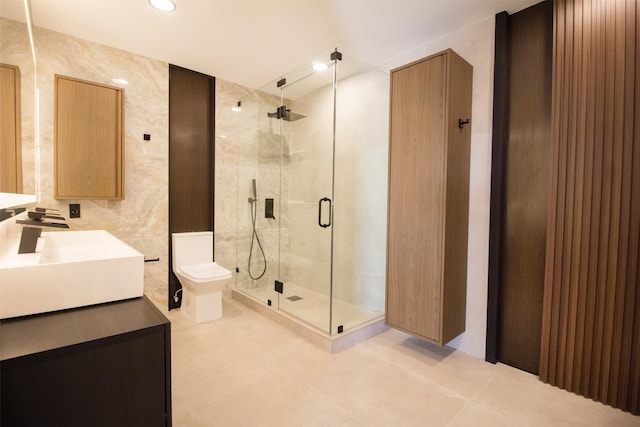 bathroom with vanity, a shower with shower door, toilet, and tile walls