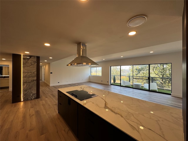 kitchen with light hardwood / wood-style floors, black electric cooktop, island exhaust hood, and light stone countertops