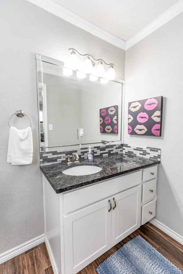 bathroom featuring vanity, crown molding, hardwood / wood-style flooring, and tasteful backsplash