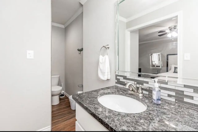 bathroom featuring tasteful backsplash, hardwood / wood-style floors, toilet, vanity, and crown molding