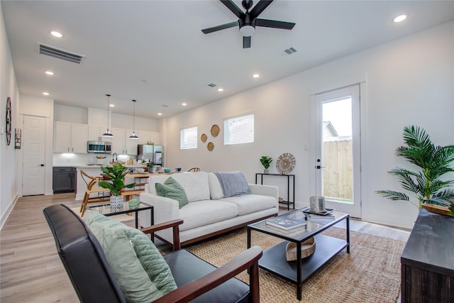 living room with ceiling fan and light hardwood / wood-style flooring