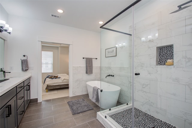 bathroom featuring tile walls, tile patterned floors, vanity, and separate shower and tub