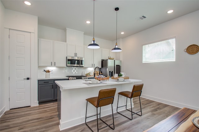 kitchen featuring gray cabinets, stainless steel appliances, light wood-type flooring, and a kitchen island with sink