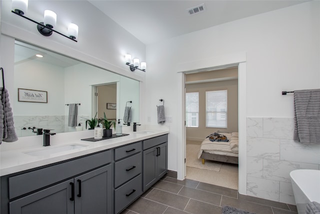 bathroom with tile walls, tile patterned flooring, vanity, and a washtub