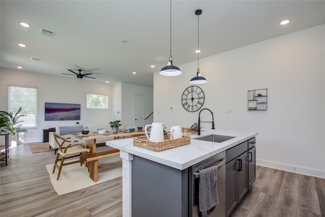 kitchen featuring pendant lighting, light wood-type flooring, sink, an island with sink, and gray cabinetry