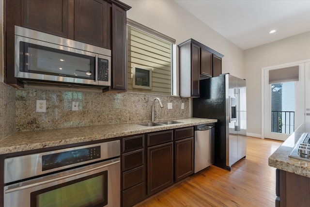 kitchen with sink, light hardwood / wood-style flooring, tasteful backsplash, dark brown cabinets, and stainless steel appliances