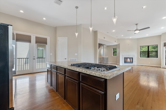 kitchen with hanging light fixtures, light hardwood / wood-style flooring, ceiling fan, a kitchen island, and stainless steel appliances