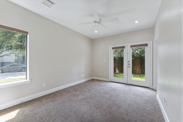 carpeted spare room featuring ceiling fan and french doors