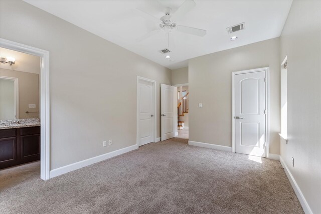 unfurnished bedroom with ceiling fan, light colored carpet, sink, and connected bathroom