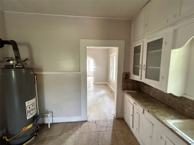 kitchen with gas water heater, white cabinetry, and sink