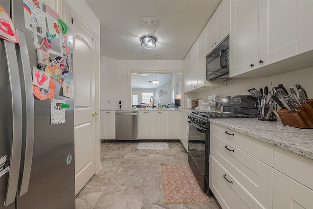 kitchen featuring light stone counters, a textured ceiling, sink, white cabinets, and black appliances