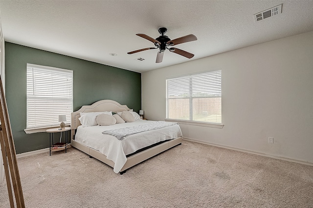 carpeted bedroom featuring multiple windows, a textured ceiling, and ceiling fan