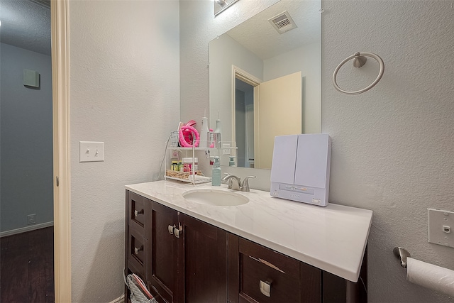 bathroom with a textured ceiling, vanity, and hardwood / wood-style floors