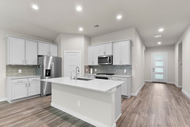 kitchen featuring light wood-type flooring, sink, white cabinets, a center island with sink, and appliances with stainless steel finishes