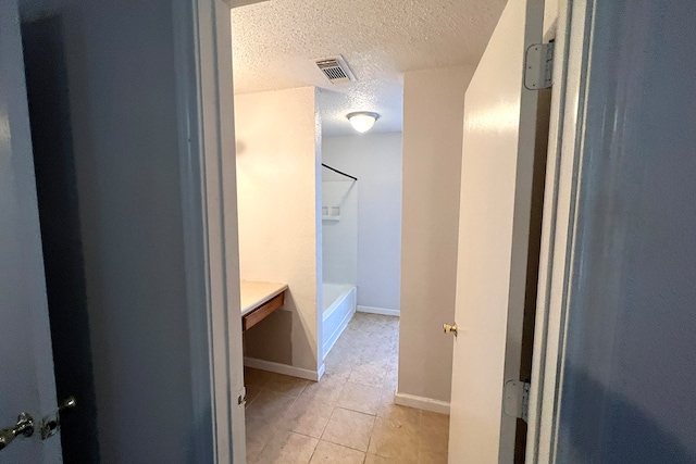 bathroom with a textured ceiling, a washtub, and tile patterned floors