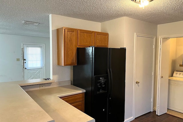 kitchen with washer / clothes dryer, black fridge with ice dispenser, dark hardwood / wood-style floors, and a textured ceiling