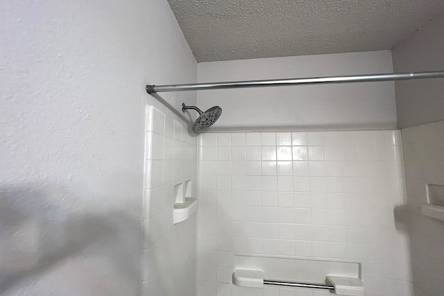 bathroom with a textured ceiling and tiled shower