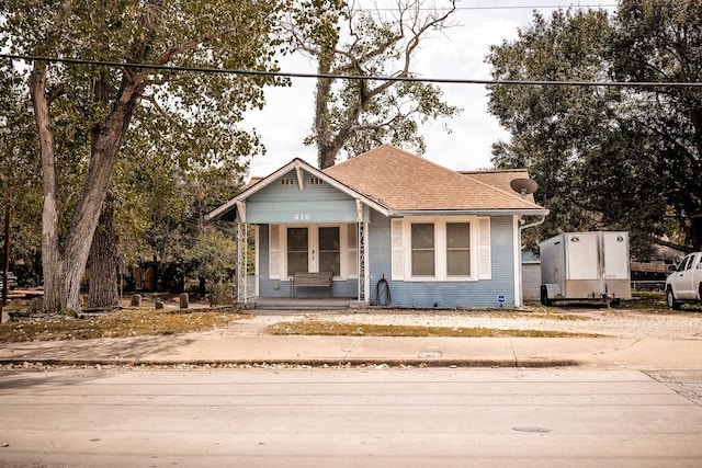 bungalow-style home with roof with shingles and a porch