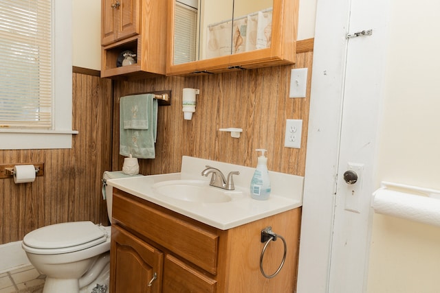 bathroom featuring vanity, wood walls, toilet, and tile patterned floors