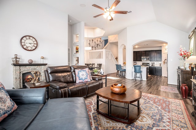 living room featuring ceiling fan, a fireplace, dark wood-type flooring, and lofted ceiling